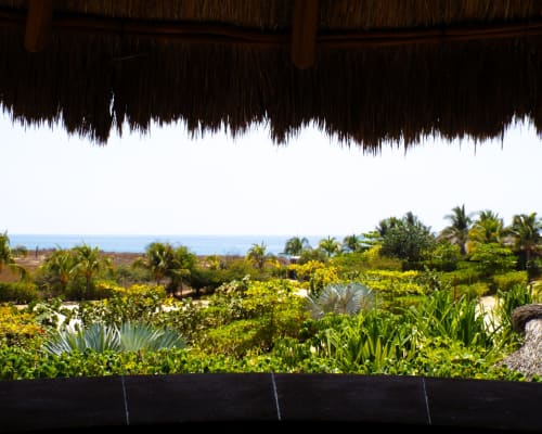 Vista al océano desde apartamento de El Origen Villas Puerto Escondido, con exuberantes jardines tropicales y palmeras frente al mar