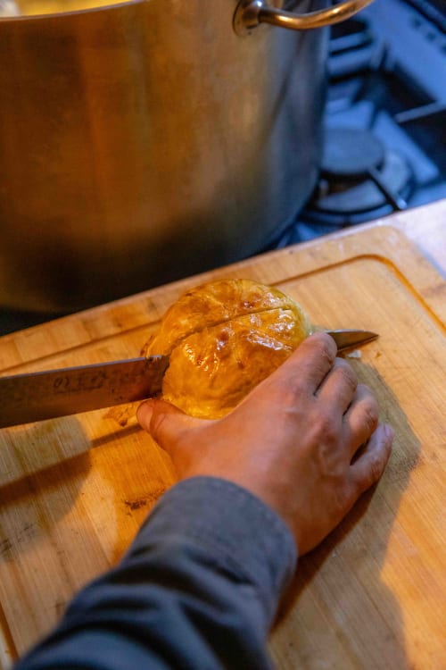 Hand slicing fresh croissant on wooden board at Moulin de Gaubourg bed and breakfast in Anjou wine region