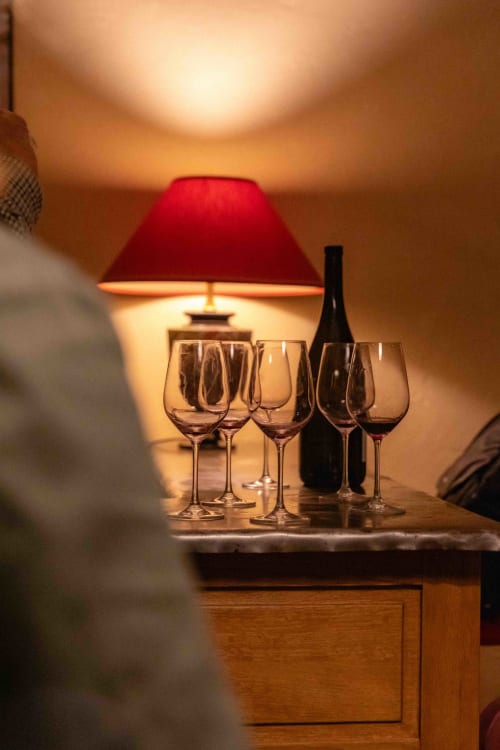 Elegant wine glasses and bottle on table with red lamp at Moulin de Gaubourg wine country B&B in Anjou