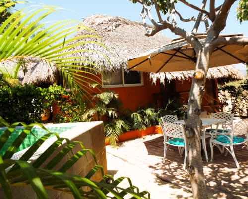 Bungalow de El Origen Villas con techo de palma, terraza privada, palmeras y vista al jardín en Puerto Escondido