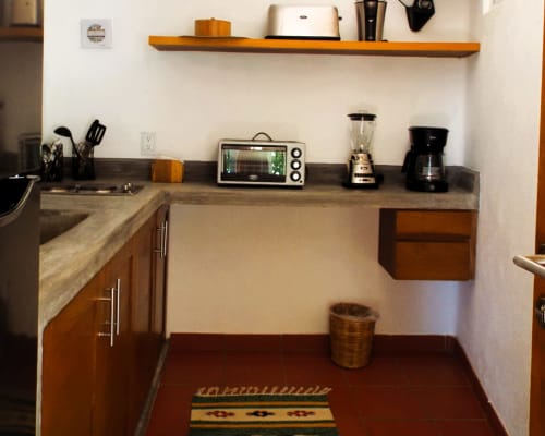 Cocina moderna en El Origen Villas con electrodomésticos de acero inoxidable, estantería de madera y encimeras de granito en Puerto