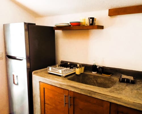 Cocina compacta en bungalow de El Origen Villas con refrigerador de acero inoxidable, encimeras de madera y fregadero