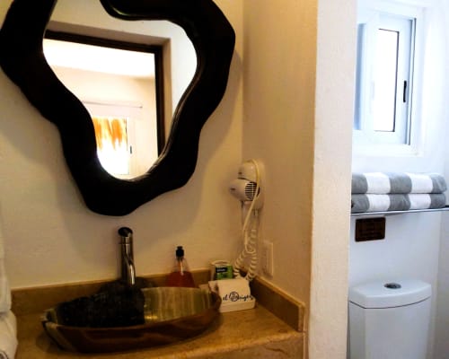 Baño moderno en El Origen Villas con espejo marco negro elegante, lavamanos de recipiente y toallero blanco en Puerto Escondido