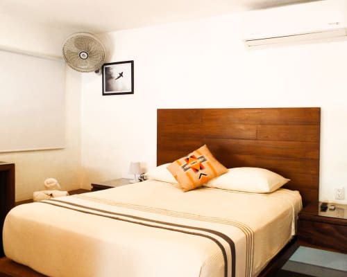 Cómodo dormitorio en El Origen Villas & Spa, Puerto Escondido, con cama de madera, ventilador de techo y vista al jardín
