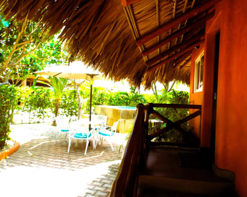 Terraza privada de El Origen Villas con tumbonas, techo de palapa y vista al jardín tropical en Puerto Escondido