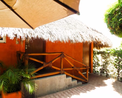 Bungalow naranja con techo de paja y terraza de madera en El Origen Villas & Spa, Puerto Escondido