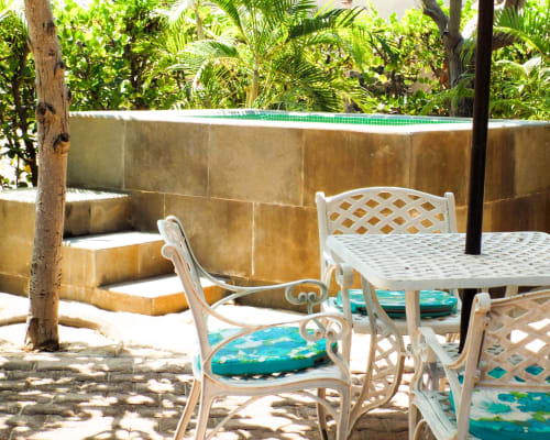 Terraza exterior de El Origen Villas con sillas de rejilla blancas, mesa de comedor y piscina Jacuzzi privada rodeada de exuberante vegetación
