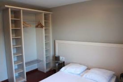 Chambre moderne aux Balcons du Sancy avec armoire et lit blancs, appartement de Picherande