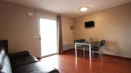 Chambre studio aux Balcons du Sancy à Picherande avec lit, bureau, TV et accès balcon par porte vitrée