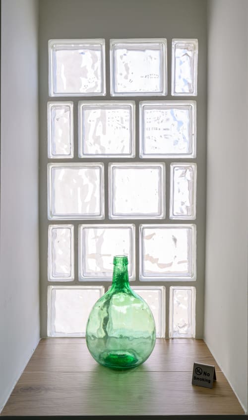 Botella de vidrio verde en hornacina de hotel con ventana de bloques de vidrio en Hotel Boutique Alcazaba Salobreña