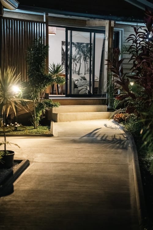 Entrée de Studio les Orangers la nuit, Ô Coeur de l'Ouest, avec plantes tropicales illuminées et cadres noirs modernes