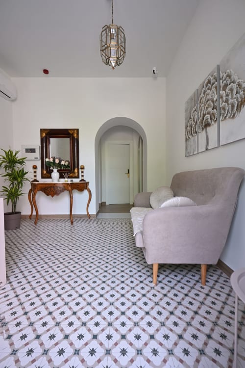 Elegante entrada del hotel Alcazaba Salobreña con consola vintage, puerta arqueada y baldosas decorativas