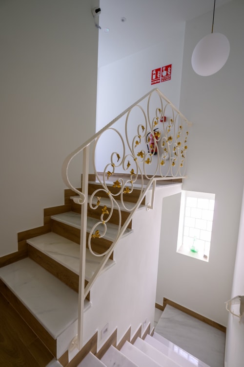 Elegante escalera blanca con barandal de hierro forjado decorativo en Hotel Boutique Alcazaba, Salobreña