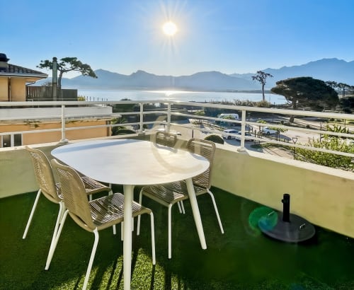 Terrasse ensoleillée avec table de salle à manger donnant sur la baie d'Île-Rousse et les montagnes, appartement meublé avec vue sur mer