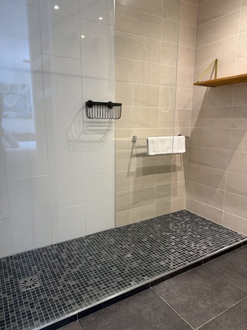 Modern walk-in shower at Villa Limone Calenzana with tiled floor, glass enclosure, and wooden shelf