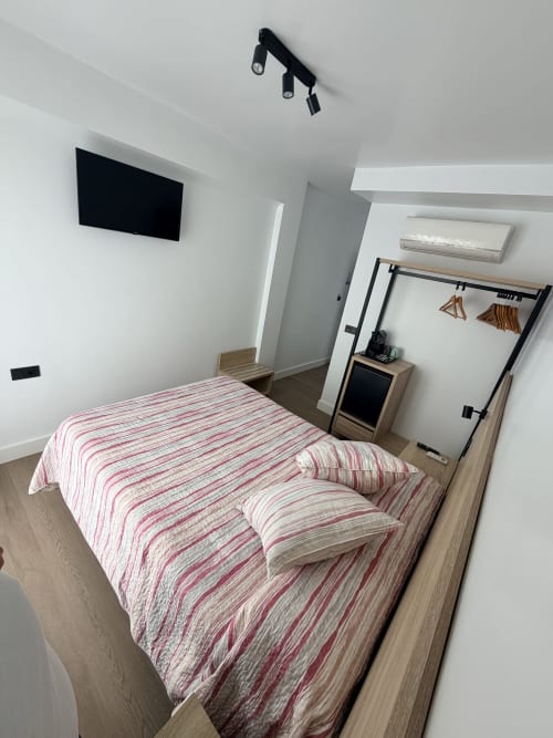 Habitación moderna en Hostal Juan Carlos de Carboneras con ropa de cama a rayas, TV en pared y muebles de madera