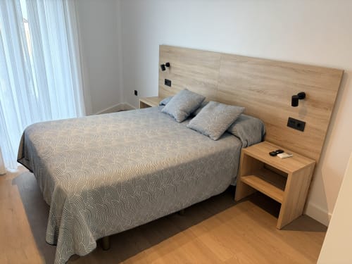 Habitación moderna en el Hostal Juan Carlos de Carboneras con cabecero de madera, ropa de cama estampada y mesita de noche