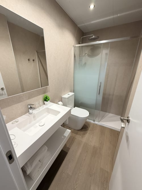 Baño moderno del Hostal Juan Carlos en Carboneras con tocador blanco, inodoro y cabina de ducha de cristal