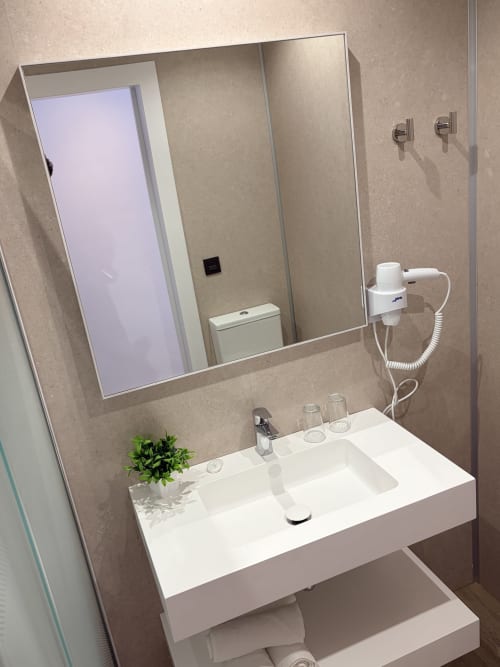 Baño moderno del Hostal Juan Carlos en Carboneras con lavamanos blanco, espejo grande y accesorios contemporáneos