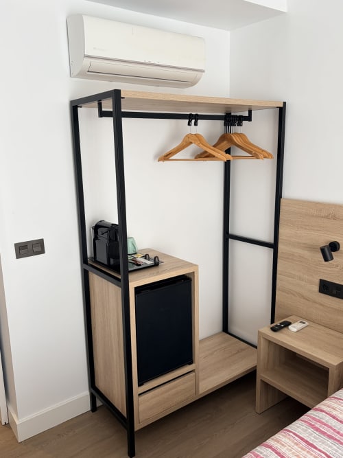 Moderno guardarropa de madera con marco negro y barra de colgar en el Hostal Juan Carlos, Carboneras. Perchas de madera visibles