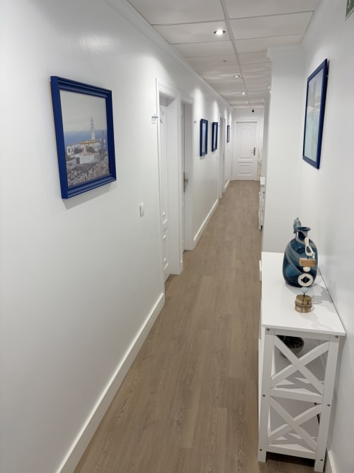 Pasillo blanco y limpio del Hostal Juan Carlos en Carboneras con fotos costeras de marco azul y decoración náutica