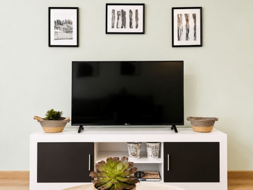 Sala de estar moderna con televisor de pantalla plana y consola multimedia blanca en apartamento de Baiona