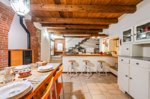 Cucina rustica con travi in legno, tavolo arancione, mobili bianchi e bancone bar presso hotel di Verona
