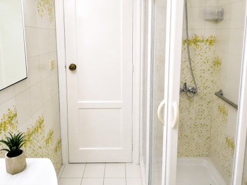 Baño con ducha del apartamento Mencer en Holibai, Baiona, con azulejos blancos y detalles de mosaico amarillo