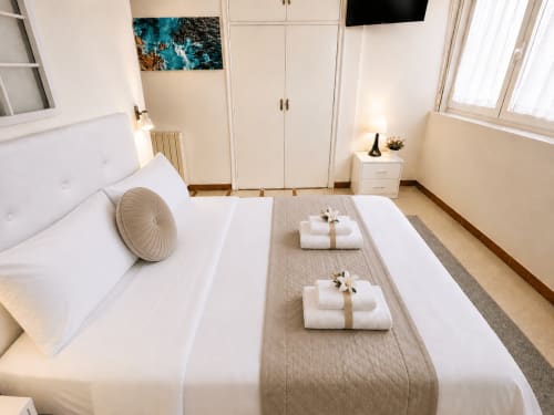 Dormitorio luminoso en apartamento Mencer, Baiona con camas gemelas, sábanas blancas, almohada enrollada, toallas dobladas, armario y vistas al mar