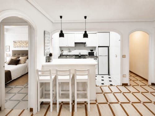 Cocina moderna y comedor en apartamento Mencer, Baiona con muebles blancos, barra y sala de estar diáfana