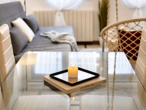 Sala de estar moderna del apartamento Baiona con vela encendida en la mesa, sofá y vistas al mar en Holibai