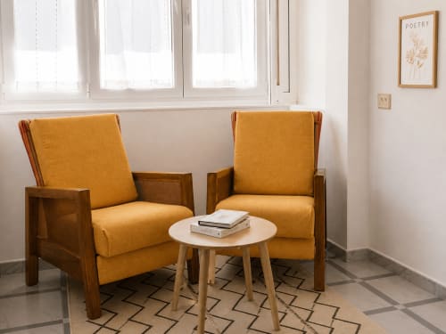 Luminosa sala de estar del apartamento Holibai con dos butacas amarillo dorado y mesa redonda de madera, Baiona