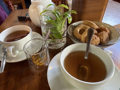 Tea service at Golden Mermaid Villa with fresh mint, cookies, and hot beverages on wooden table