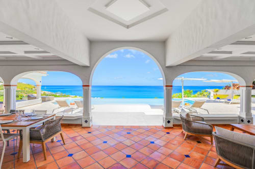 Élégant salon avec vue mer de la Villa Agama, ouvertures en arche donnant sur l'océan turquoise et la plage