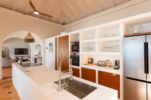 Cuisine de villa moderne avec rangements blancs, détails bois, appareils inox et espace ouvert à Villa Agama