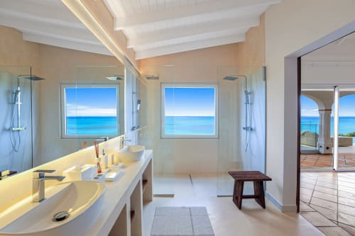 Salle de bain luxueuse avec vue sur mer à la Villa Agama : double vasque, douche à l'italienne et vue turquoise sur l'océan