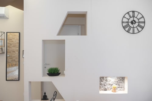 Nicchia moderna in camera d'hotel con pianta grassa in vaso, orologio da parete, ripiani decorativi e arredamento minimalista all'Elite Apartment