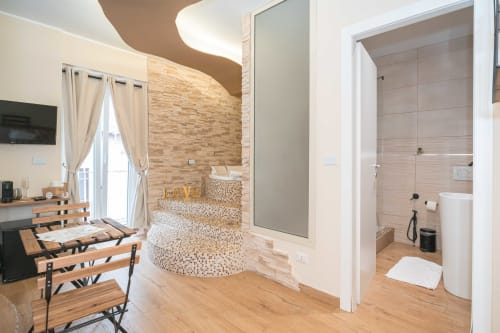 Camera da letto moderna con vasca Jacuzzi, pavimenti in legno, muro in laterizio e zona pranzo presso Elite Apartment SPA