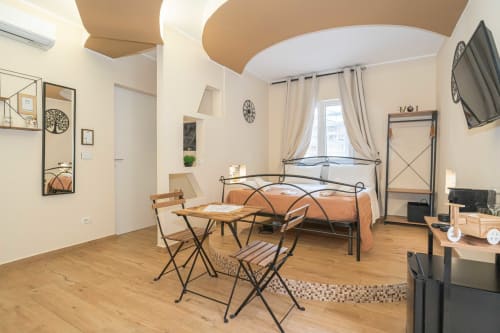 Ampia camera matrimoniale all'Elite Apartment SPA di Catania con letto in metallo, zona pranzo, pavimenti in legno e comfort moderni
