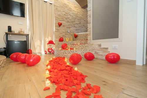 Romantica decorazione di San Valentino nella spa dell'Elite Apartment con palloncini rossi a forma di cuore e petali su pavimento in legno, Catania