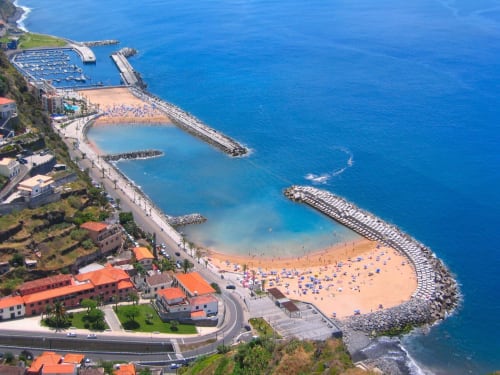 Vista aérea do resort de praia BHF Residences em Arco da Calheta, Portugal com praia de areia, piscinas e oceano azul