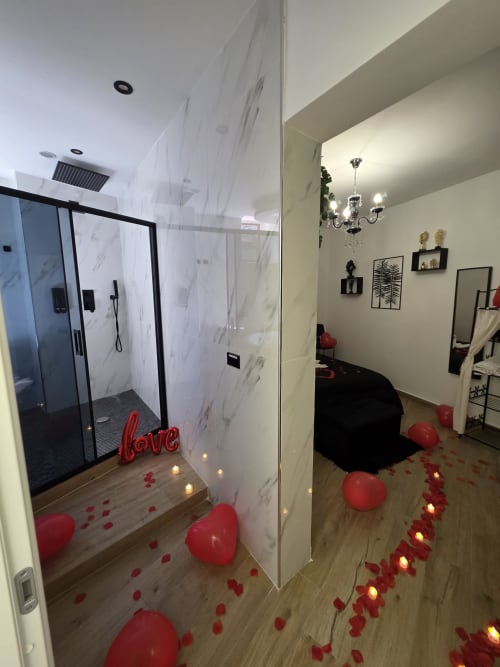 Bagno romantico all'Elite Apartment SPA di Catania con doccia in marmo, palloncini a forma di cuore rossi, petali e candele