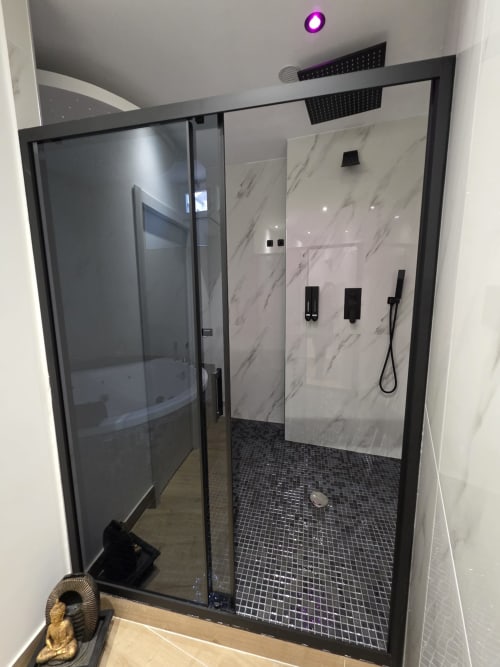 Lussuosa cabina doccia con struttura nera, rivestimenti in marmo, soffione pioggia e pavimento a mosaico presso Elite Apartment SPA, Catania