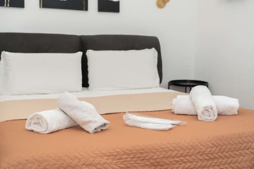 Appartamento di lusso SPA con letto king, asciugamani bianchi arrotolati e servizi disposti su copriletto beige, Catania