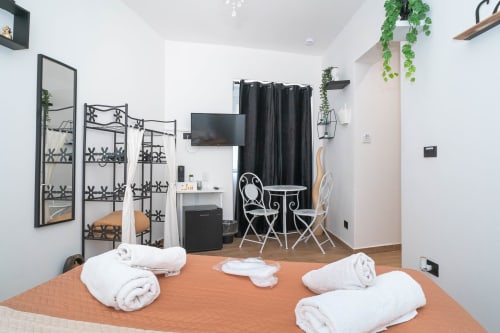 Camera da letto moderna con letto king presso Elite Apartment SPA a Catania, con asciugamani bianchi, TV, zona living e servizi spa