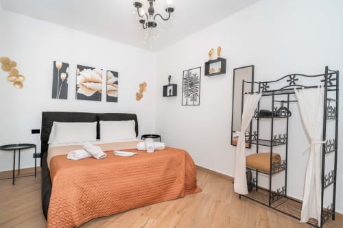 Camera da letto King SPA di lusso a Catania con letto a baldacchino, plaid arancione, arredamento moderno e servizi spa
