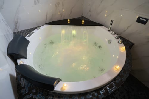 Lussuosa vasca idromassaggio rotonda con acqua effervescente e illuminazione ambientale nella suite Camera King della SPA di Elite Apartment a Catania