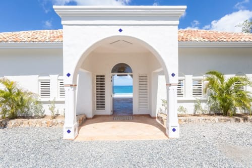 Entrée méditerranéenne blanche de Villa Agama avec porte en arche encadrant la vue sur l'océan, Saint-Martin