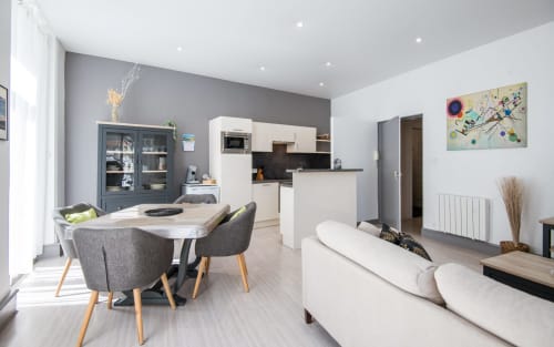 Modern open-plan apartment in Millau with dining area, kitchen, and lounge space featuring contemporary furnishings