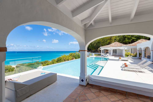 La terrasse face à l'océan de Villa Agama avec piscine à débordement, architecture blanche, eaux turquoise des Caraïbes et transats